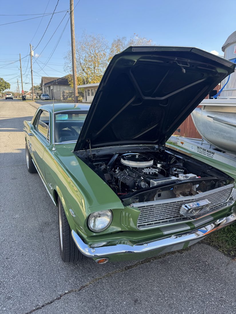 Classic green Mustang parked on a street with the hood open for on-site diagnostics
